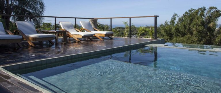 pisos e revestimentos imagem de piscina com pedra hijau durante o dia com duas cadeiras de descanso