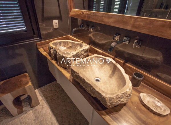 projeto de banheiro elegante com pia de madeira petrificada e piso revestido por pedras naturais