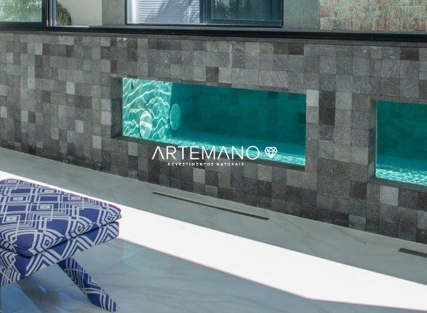pedra hitam artemano revestindo area externa da piscina em perfeita harmonia com a decoração dos bancos azuis