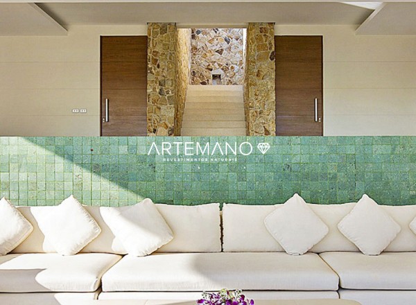 pedra hijau aplicada como revestimento para parede interna em harmonia com o sofá branco e as demais pedras que revestem o ambiente