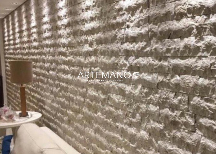 Sala de estar com grande painel de mármore travertino rockface Artemano Revestimentos Naturais.