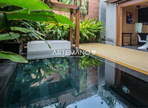 Neste projeto há um misto de espelho d'água com pedra Hitam e piscina, ao redor há muitas folhagens e o deck de madeira em perfeita harmonia.